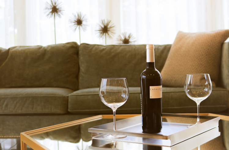 Green sofa with wine bottle and glasses – red wine spill stain removal Sydney