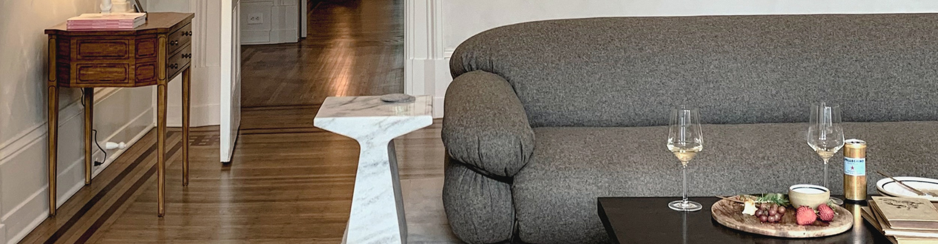 Lounge rom with grey sofa and wine glasses on brown table
