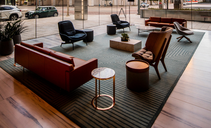 Large space with red sofas, brown and black armchairs on green and black rug