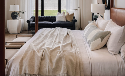 Bedroom with cream bedding and a blue sofa