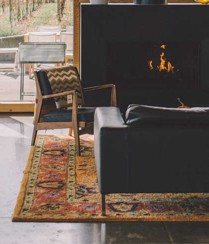 Rug cleaning Sydney – patterned rug near fireplace and black leather sofa